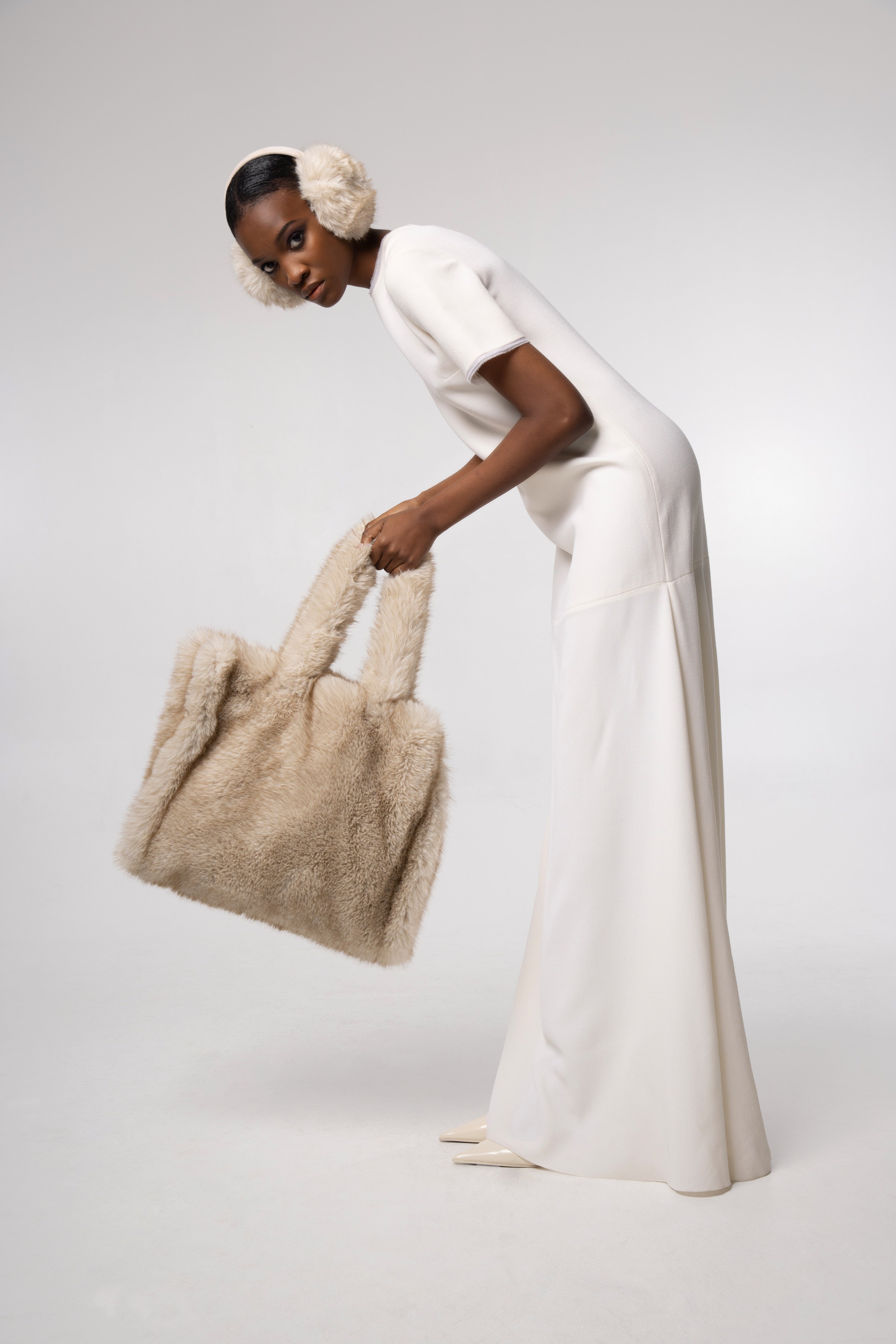Editorial shot — Ear Muffs in Fox worn by a model, showcasing the soft texture and warm neutral beige tone as a stylish winter accessory.