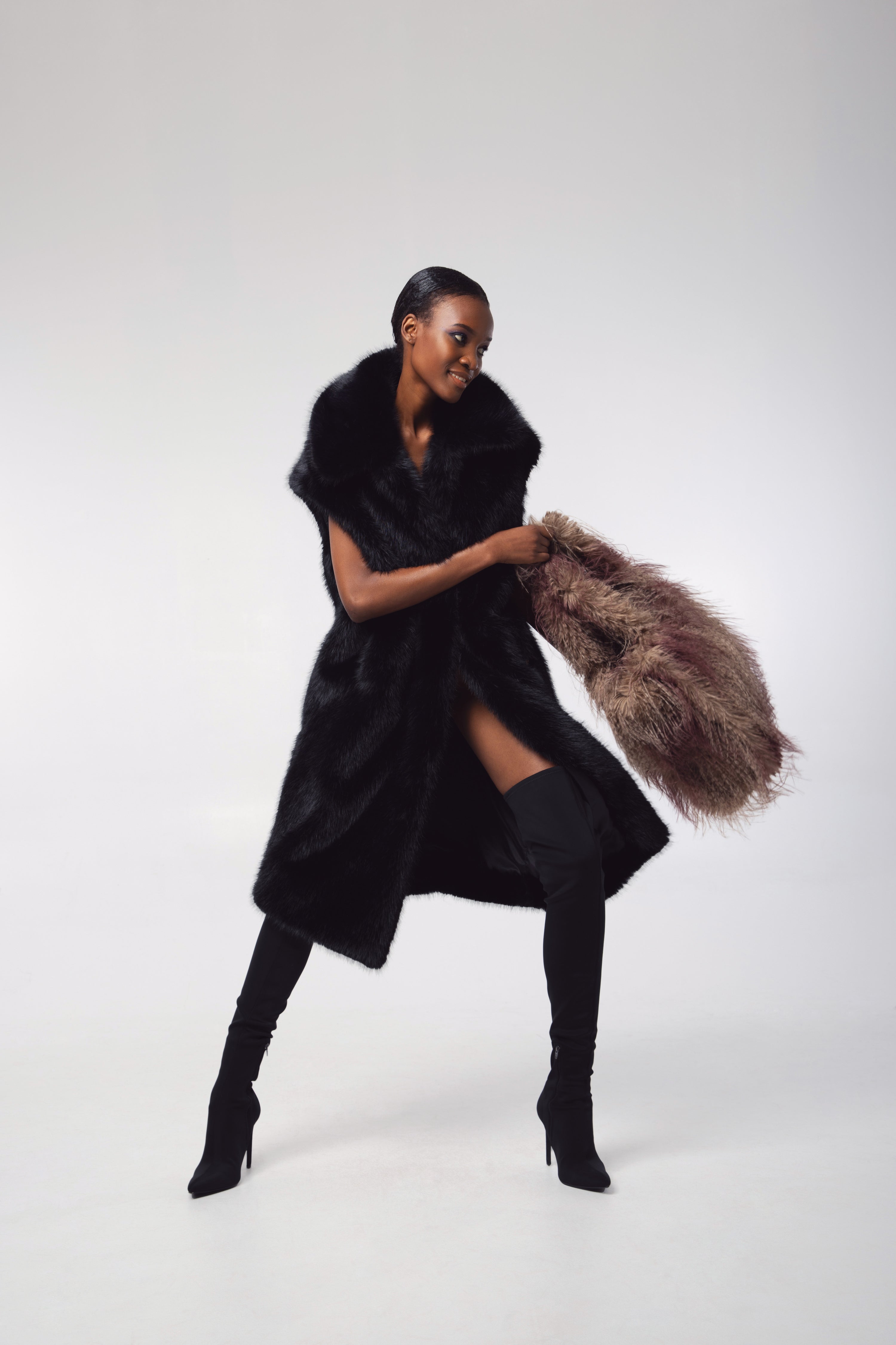 Editorial shot — KIT in Ink Black captured in motion, showcasing the coat’s flowing silhouette and luxurious faux fur texture.