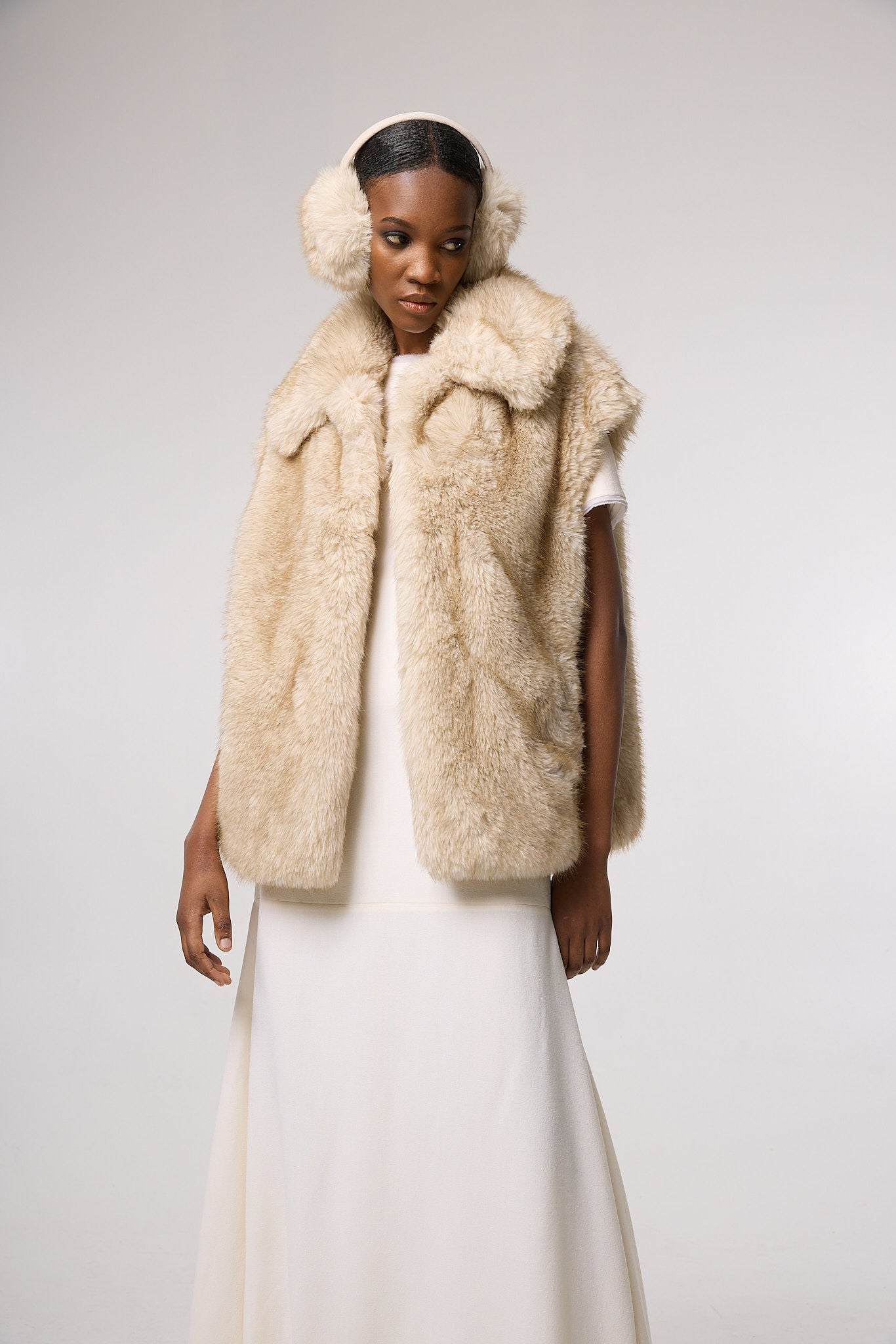 Editorial shot — MIA in Fox styled with tonal layers and ear muffs, showcasing the plush faux fur texture and warm beige hue.