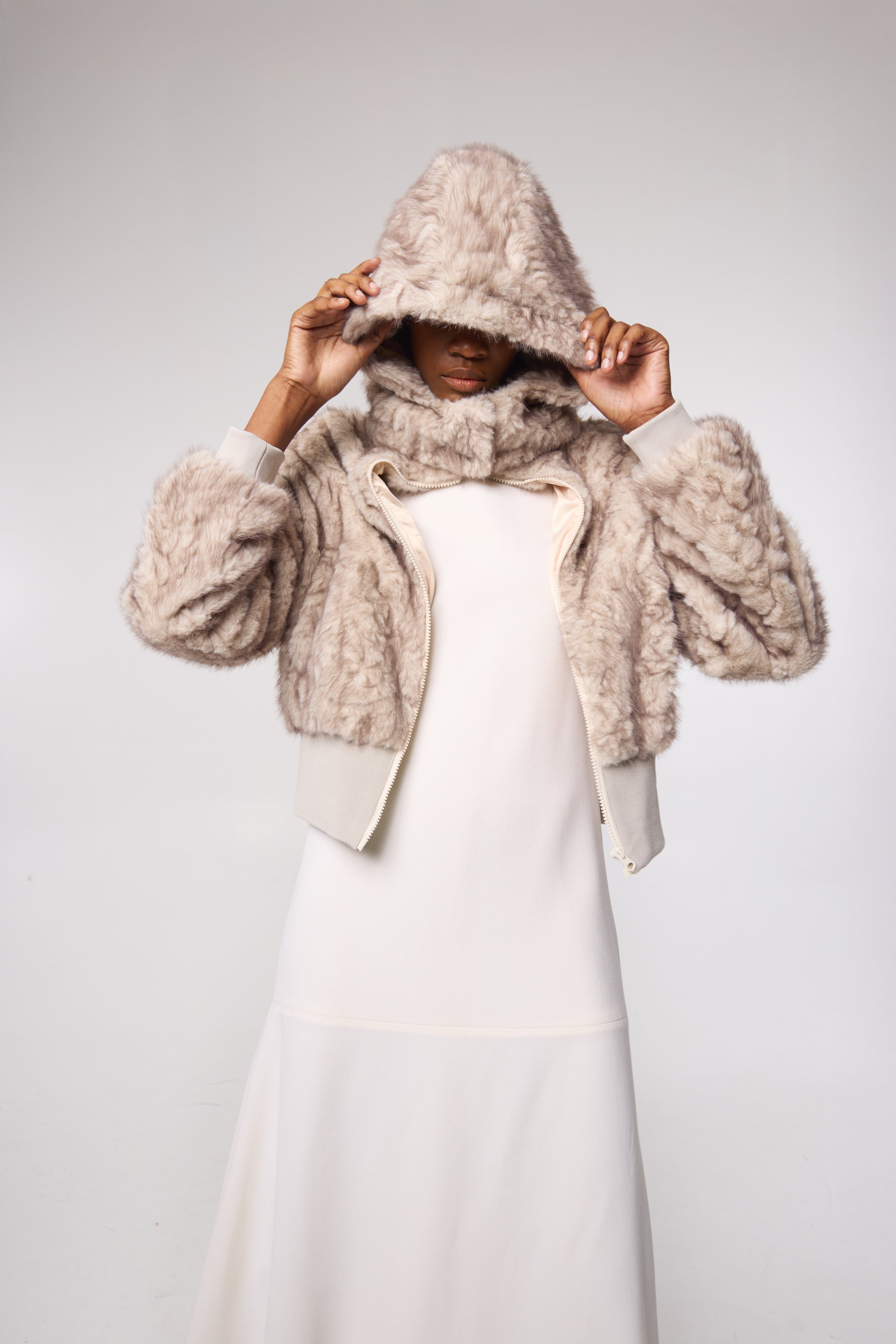 Editorial shot — FIONA in Husky styled with tonal layers, emphasizing the dramatic hood, voluminous silhouette, and luxe faux fur texture.