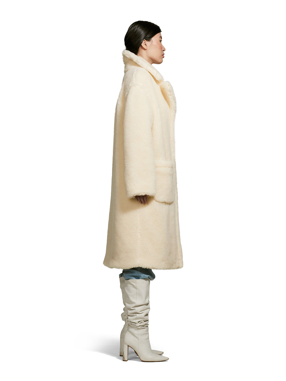 Female model wearing a teddy-inspired faux-fur sherpa shell in cream color on a white background from the side.